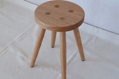 a small wooden stool sitting on top of a white sheet