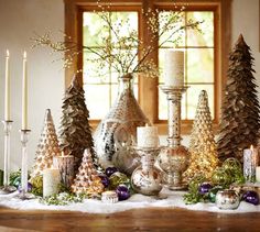 a table topped with lots of different types of christmas trees next to candles and other decorations