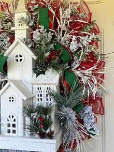 a christmas wreath with a church and evergreens hanging on the front door to welcome guests