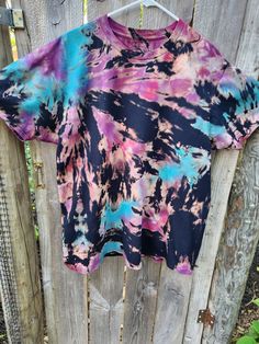 a tie dyed shirt hanging on a wooden fence