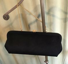 "This is a vintage, black purse, from the 50s or 60s. No labels or names inside. The purse has a single center compartment. The purse is made of black fabric. The hardware & optional chain handles are gold tone metal & it closes with a push clasp with a rhinestone centerpiece. The bag measures 5.5\" tall, 1-1/2\" across the bottom, and 12\" wide. Handle drop measures 5.5\". Inside is lined with fabric & the handle can be tucked inside for use as a clutch. It is in good, vintage condi Classic Rectangular Evening Bag For Vintage Events, Vintage Formal Clutch With Chain Strap, Vintage Black Rectangular Evening Bag, Vintage Evening Bag With Chain Strap For Formal Occasions, Vintage Black Clutch For Evening, Vintage Black Evening Clutch, Retro Black Evening Bag For Formal Occasions, Elegant Vintage Black Bag For Formal Occasions, Elegant Vintage Black Formal Bag