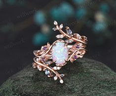 an opal and diamond ring sitting on top of a rock