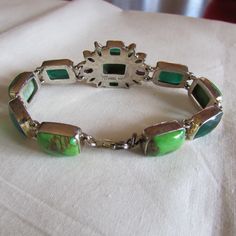 "Sterling silver link bracelet with two amethyst faceted stones and various green stones. There are dark green cushion cut stones, lime green cabs, and two colors of faceted small marquis stones. Some look like peridot. Stamped IB India 925. The center cluster is 1\" tall x 1 1/8\" wide. The length of the bracelet is 8\". Lobster claw clasp. Good condition. Shipped by US mail. LB-1" Modern Green Cabochon Jewelry, Green Cabochon Bracelet For Formal Occasions, Green Cabochon Bracelets For Formal Occasions, Modern Green Jewelry With Gemstone Accents, Green Cabochon Bracelets As A Gift, Green Cabochon Bracelets For Gift, Elegant Green Cabochon Bracelets, Formal Green Cabochon Bracelets, Formal Green Cabochon Bracelet