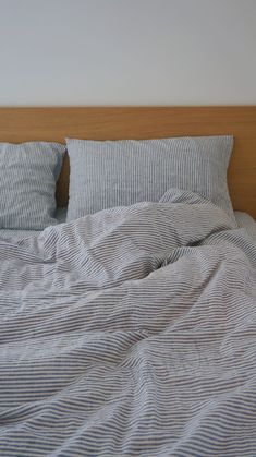 an unmade bed with blue and white striped sheets