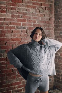 Model wearing oversized cable sweater in light grey alpaca wool, front Gray Oversized Cozy Sweater, Oversized Gray Wool Sweater, Oversized Gray Cashmere Sweater, Gray Funnel Neck Winter Sweater, Gray Funnel Neck Sweater For Winter, Oversized High Neck Cable Knit Sweater, Snug Gray Winter Sweater, Oversized Gray Turtleneck Outerwear, Cozy Cable Knit Sweater With Funnel Neck