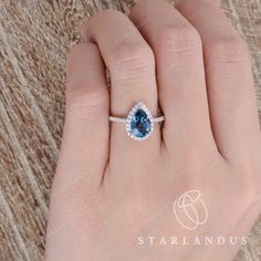 a woman's hand with a blue and white diamond ring on top of it