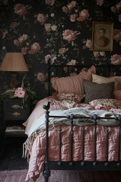 a bedroom with floral wallpaper and pink bedspread in front of a black headboard