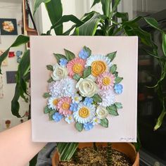 a potted plant with flowers in it on top of a table next to a painting