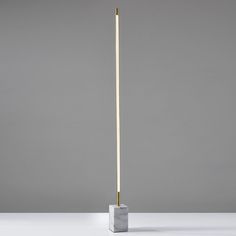 a white and gold floor lamp on a grey background