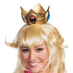 a woman with blonde hair wearing a gold crown and pink shirt smiling at the camera