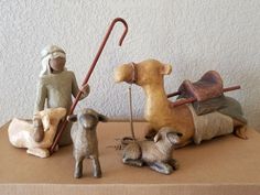 three ceramic figurines are sitting on top of a cardboard box with a shovel