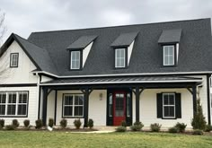 a white house with black shingles and red door