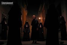 a group of people dressed in nun costumes standing on the street at night with one person holding a lantern