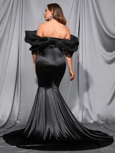 the back of a woman in a black evening gown, with her hands on her hips