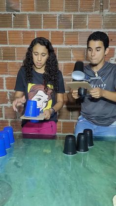 two people sitting at a table with cups