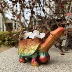 a colorful turtle planter with flowers in it