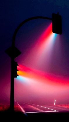 a traffic light sitting on the side of a road next to a tall pole with street lights