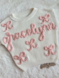 a white sweater with pink bows and the words happy on it