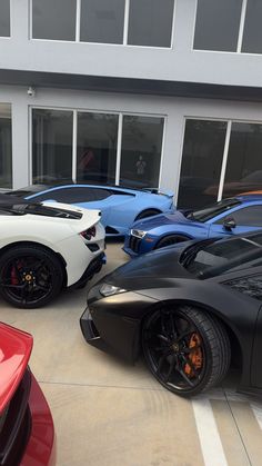 several different colored sports cars parked next to each other in front of a large building