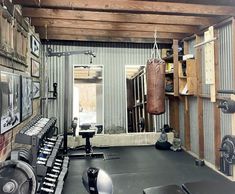 a gym with several machines and boxing gloves hanging from the ceiling in front of a mirror