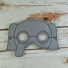 a felt mask with two holes in the middle on a wooden surface, cut out to look like an elephant's head