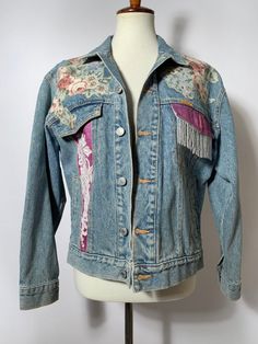 Jordache Vintage Jean Jacket  Take me back to the 80s and 90s! Such a fun statement piece. Floral detailing all over jacket.  --- Condition: Great Vintage Condition. Few normal signs of vintage wear.  --- Size: Fits M best  Shown on size small mannequin  --- All items are uploaded to Instagram first. Follow @bluehoneyshop for first dibs! Retro Spring Outerwear With Patches, Vintage Long Sleeve Denim Jacket For Spring, Vintage Denim Jacket With Graphic Print For Spring, Vintage Graphic Print Denim Jacket For Spring, Retro Spring Denim Jacket With Patches, Spring Retro Denim Jacket With Patches, Retro Graphic Print Outerwear For Spring, Retro Spring Outerwear With Graphic Print, Spring Vintage Denim Jacket For Festival