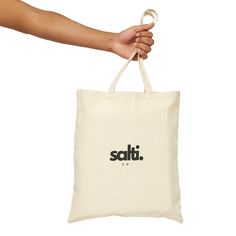 a hand holding a white bag with the word salt on it and black lettering that says salt