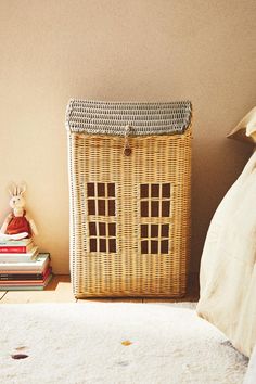 a wicker basket sitting on top of a bed next to a stuffed animal and books