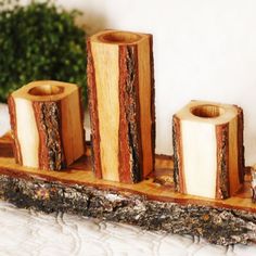 three wooden candles are sitting on a piece of wood that has been cut into smaller pieces