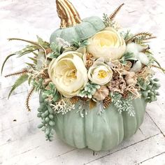 a green pumpkin decorated with flowers and leaves