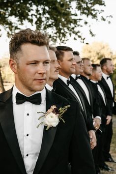 a group of men in tuxedos standing next to each other wearing black suits and bow ties