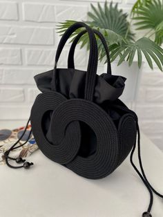 a black handbag sitting on top of a table next to a potted plant