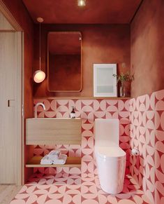 a bathroom with pink and white tiles on the floor, sink, toilet and mirror