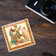 an old camera and some stickers on a wooden table next to a polaroid