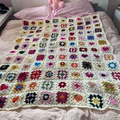 a crocheted granny blanket on a bed with a pink teddy bear in the corner