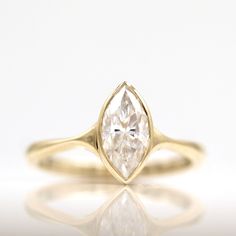 a yellow gold engagement ring with a pear shaped diamond in the center, on a white background