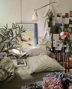 an unmade bed in a room with plants and books