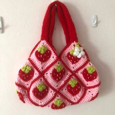 a crocheted strawberry purse hanging on the wall