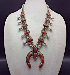 "VINTAGE NAVAJO SQUASH BLOSSOM NECKLACE DESCRIPTION: This stunning necklace features 18 oval cabochons of old red Mediterranean coral. The gemstones are secure in scalloped bezel, on a foundation of heavy gauge vintage sterling silver. Each blossom is framed with an applied leaf, applied raindrops, and a sterling silver swirl. This magnificent necklace will be a valuable addition to your collection of fine vintage Native American jewelry. MEASUREMENTS: Necklace measures 26\" end to end Naja meas Red Southwestern Style Collectible Jewelry, Traditional Red Jewelry For Collectible, Classic Handmade Red Necklace, Traditional Red Jewelry For Collectors, Red Vintage Necklace With Cabochon, Red Vintage Jewelry With Cabochon, Vintage Red Cabochon Necklace, Vintage Oval Red Jewelry, Red Vintage Cabochon Necklace