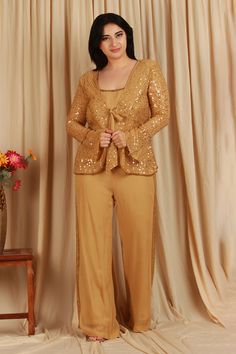 Golden jacket with sequin embellishments. Comes with top and embellished pant.
Components: 3
Pattern: Hand Embellished
Type Of Work: Sequins
Neckline: Jacket: V Neck
Sleeve Type: Jacket: Bell
Fabric: Georgette 
Color: Gold
Other Details: 
Front knotted jacket
Attached lining
Length:
Top: 22 inches
Jacket: 27 inches
Pant: 44 inches
Occasion: Party - Aza Fashions Elegant Embellished Pant Set For Festive Occasions, Glamorous Fitted Hand Embellished Palazzo Set, Elegant Pant Set For Reception With Long Sleeves, Glamorous Fitted Hand-embellished Palazzo Set, Elegant Long Sleeve Pant Set For Reception, Elegant Long Sleeve Sequin Sets, Hand Embellished Fitted Palazzo Set For Party, Embellished Palazzo Set For Evening Party Wear, Embellished Palazzo Set For Evening