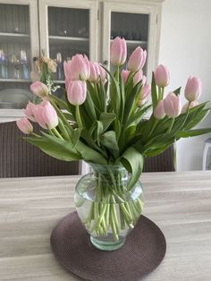 a vase filled with pink tulips on top of a wooden table