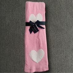 a pink towel with white hearts on it and a black ribbon tied around the edge