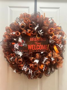 a welcome wreath is hanging on the front door with brown and orange decorations around it