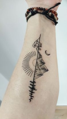 a woman's arm with a tattoo on it that has an arrow and sun