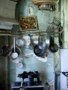 pots and pans are hanging on the wall in an old kitchen with peeling paint