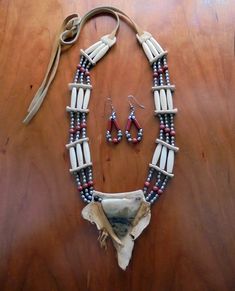 Natural materials are the basis for this beautiful, unique set from the early 1990.  Safely packed away for decades, the striking design will compliment both casual and dress outfits and bound to elicit compliments. The components include bone and the center stone is set on deerskin. Brushed silver-colored beads are interspersed with rust beads, as shown, with soft chamois straps which tie at the neck. SIZE:  The unusual colored stone pendant is approximately 1-1/2" high from the top to the point; and the deerskin patch backing is approximately 3" high. The straps measure 12" from their ends to the beads; and the beaded part to the base of the deerskin pendant is approximately 11". EARRINGS:  pierced style; silver beads with rust; 1-1/2" tall, not counting hook. CONDITION: Very Good, rarel Soft Chamois, Bone Necklace, Colored Stone, Handmade Beaded Jewelry, Deer Skin, Stone Pendant, Steel Chain, Stone Pendants, Earings Piercings