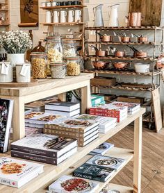 a table with many books on it in a room filled with shelves full of cookbooks