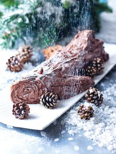 a piece of cake sitting on top of a white plate covered in frosting and pine cones