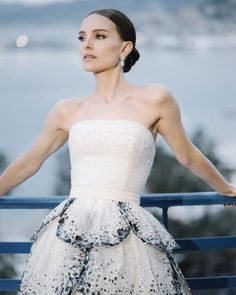 a woman in a white dress is standing on a blue railing with her arms outstretched