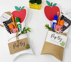 two paper bags filled with school supplies on top of a white table next to each other